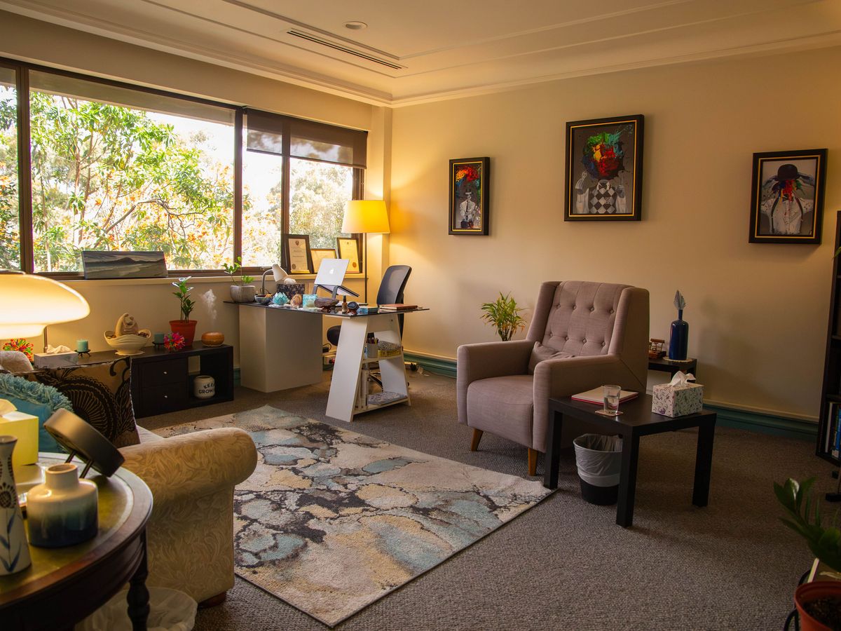 The West Perth consulting room, with a sofa, a desk and two armchairs by the window